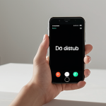A serene individual in a minimalist, peaceful setting, holding a smartphone with a clean interface showing 'Do Not Disturb' mode activated. The scene emphasizes calm focus and control over digital distractions, with soft lighting and a sense of mental clarity.